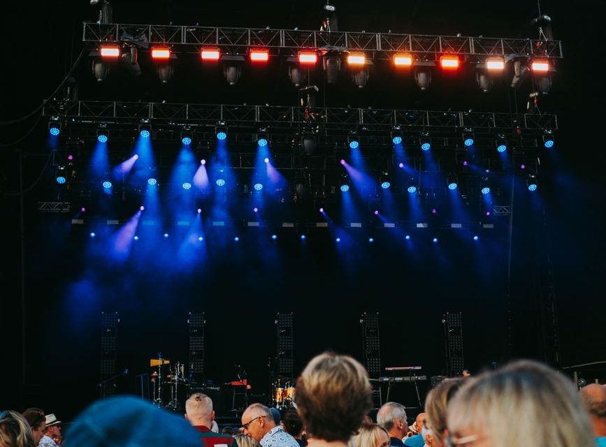 Público asistiendo a un concierto nocturno en un gran escenario al aire libre