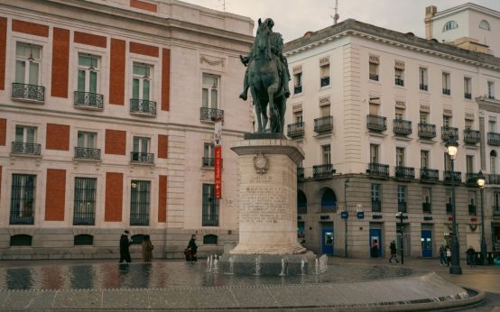 Plaza peatonal urbana con zonas verdes y árboles en Madrid