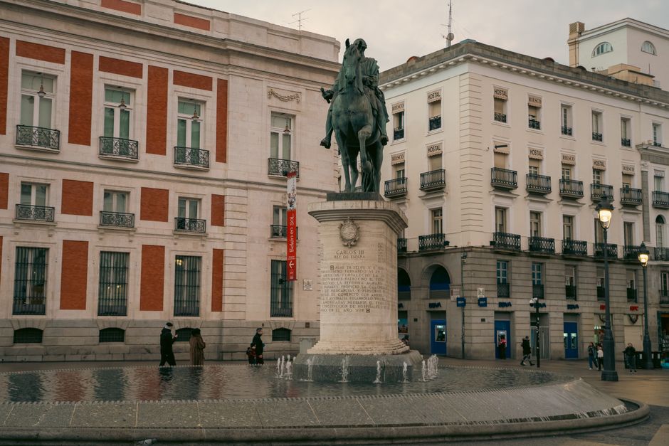 Plaza peatonal urbana con zonas verdes y árboles en Madrid