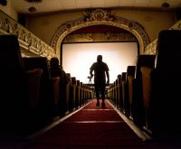 Interior de una sala de cine histórica con butacas tradicionales y proyector antiguo