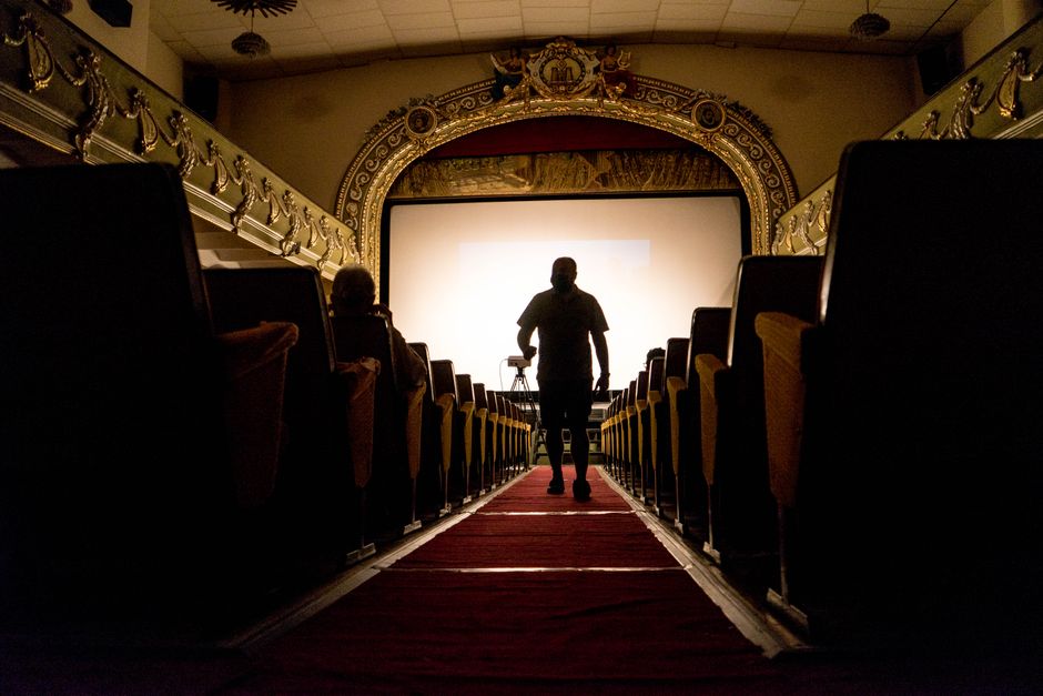 Interior de una sala de cine histórica con butacas tradicionales y proyector antiguo